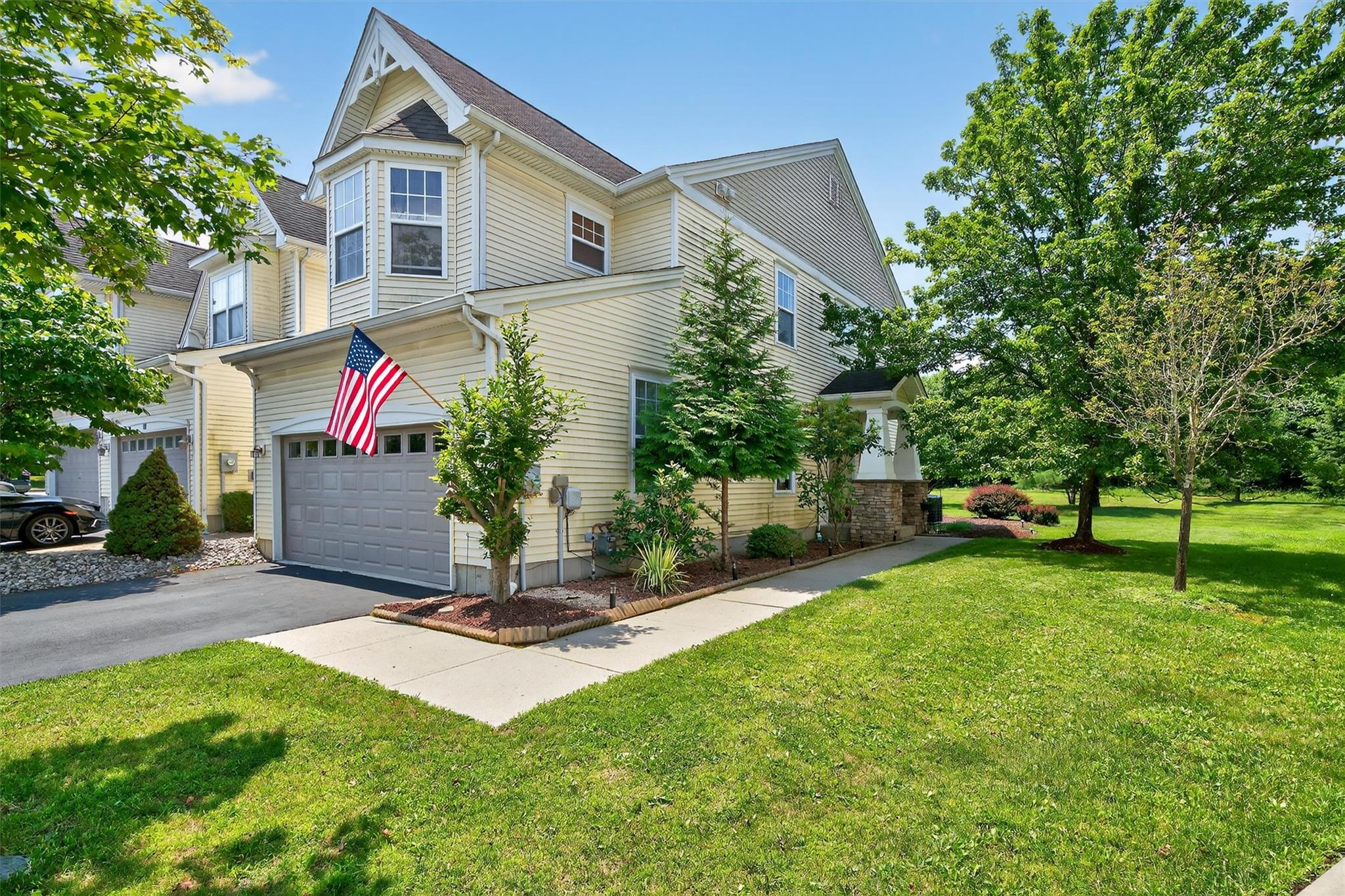View of front of house featuring asphalt driveway, a garage, and a front lawn
