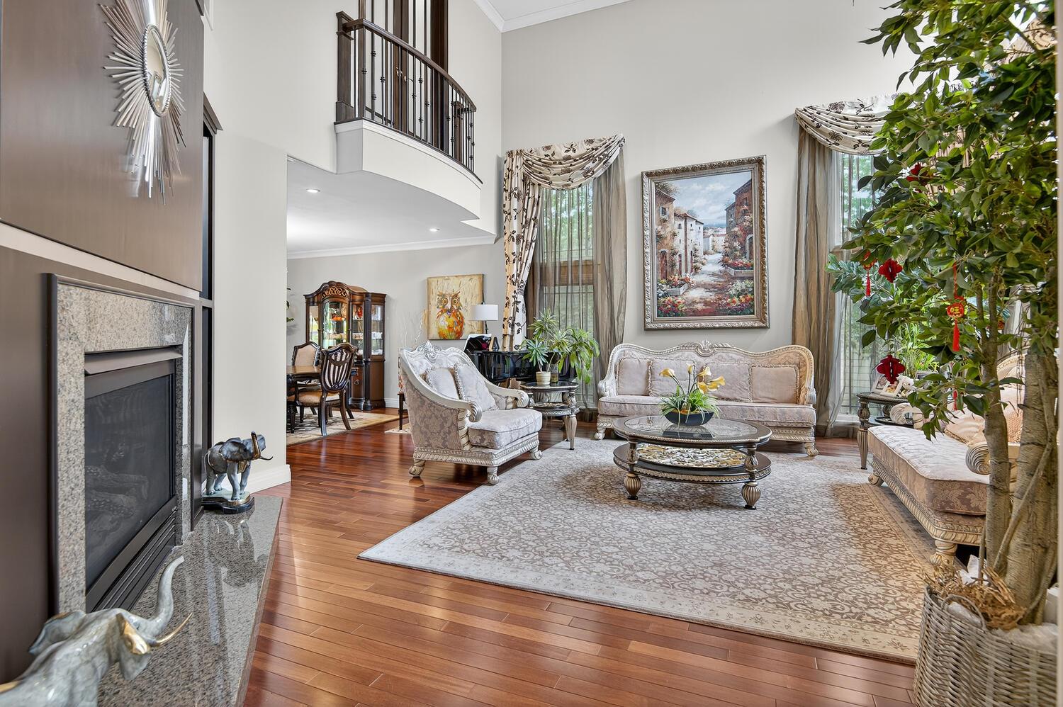 Living room with crown molding, wood-type flooring, a premium fireplace, and a high ceiling