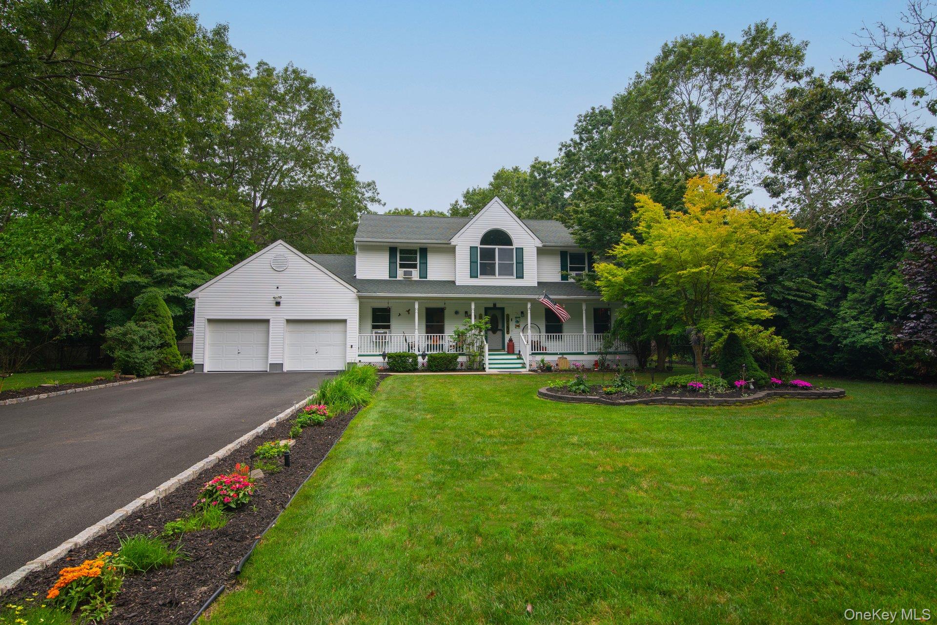 View of front of house featuring a porch, an attached garage, asphalt driveway, and a front lawn