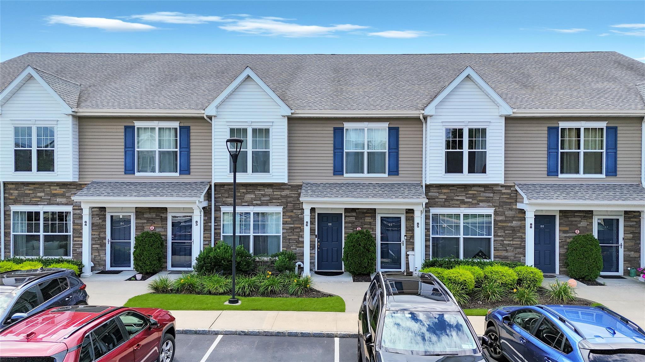 View of front of house featuring uncovered parking, stone siding, and roof with shingles