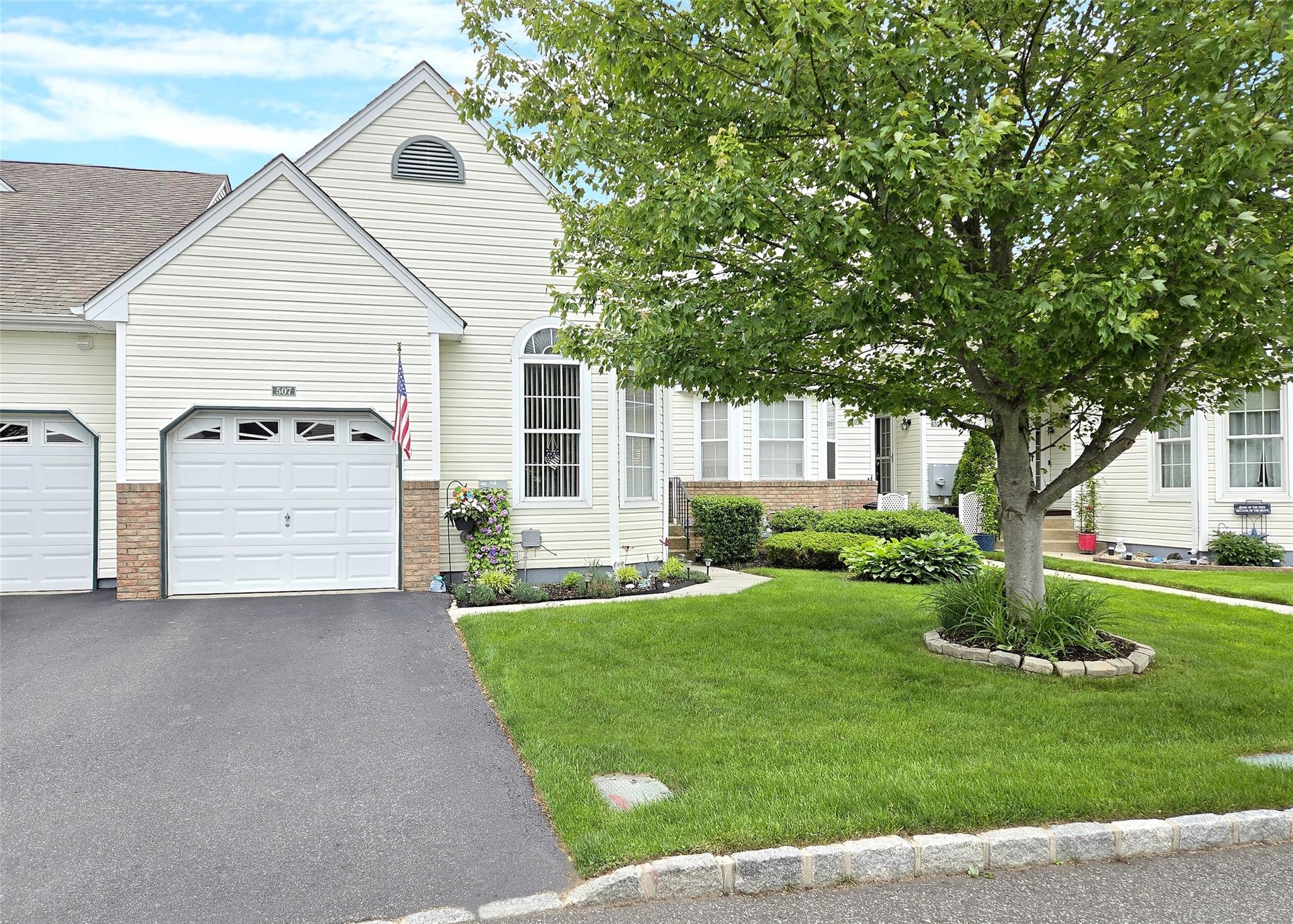 View of front of home featuring a front lawn, asphalt driveway, brick siding, and a garage