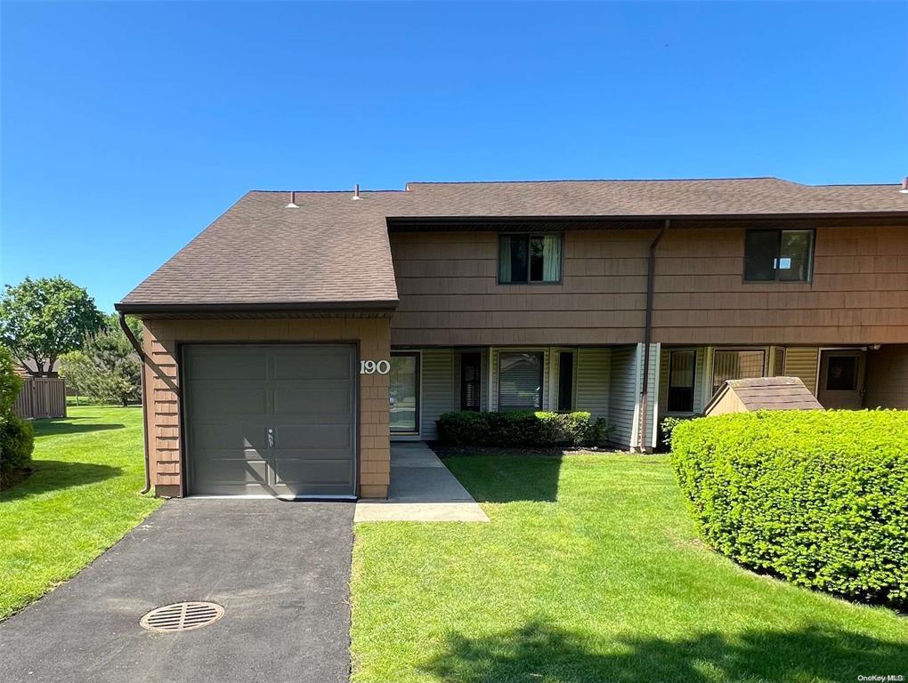Front of Condo End unit attached garage, a front lawn, driveway, and a shingled roof