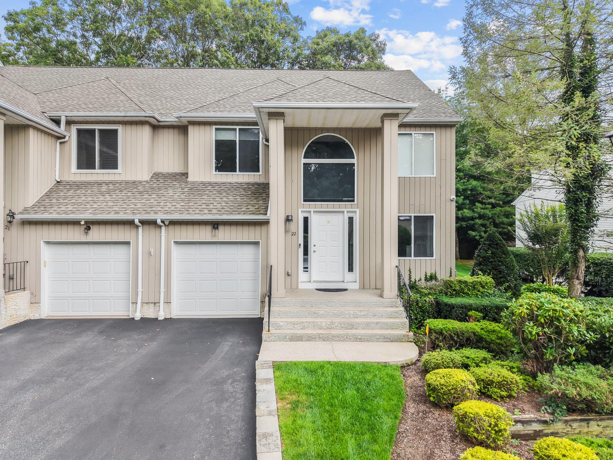 View of front facade featuring a shingled roof, driveway, and a garage
