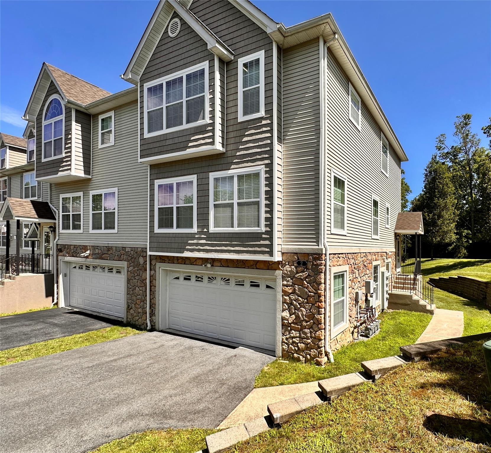 View of front of house featuring stone siding, a 2-car garage, and an asphalt driveway