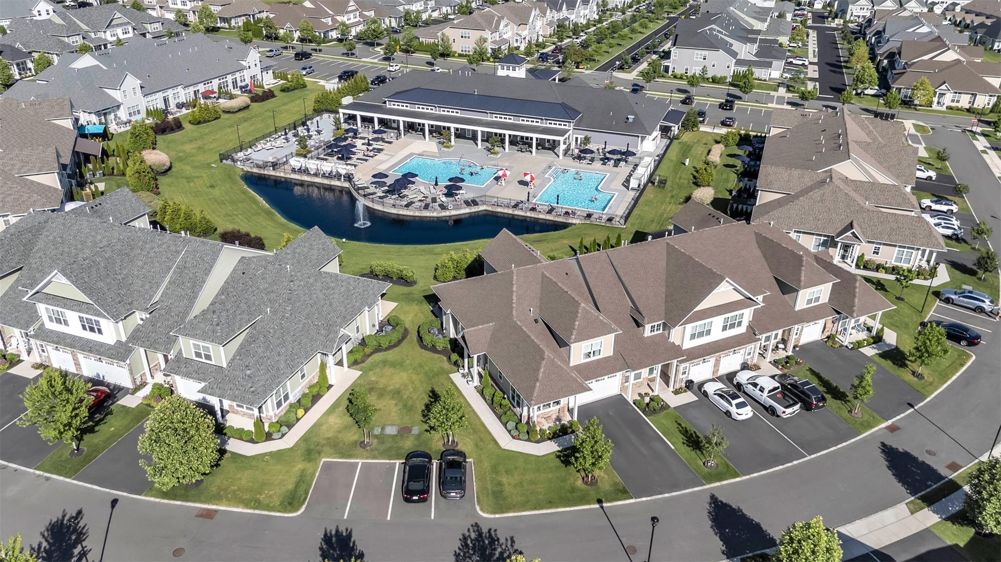 Aerial view of property's location with views of the Pond with fountain, two Pools and Clubhouse
