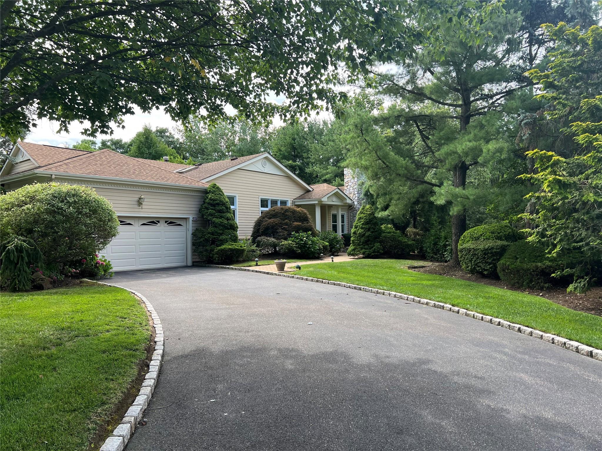 View of front of house with driveway, an attached garage, a front yard, and roof with shingles