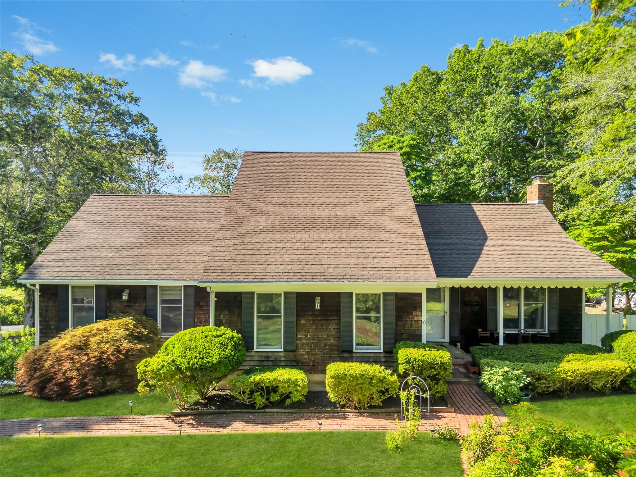 View of front of property with a chimney, a shingled roof, and a front lawn
