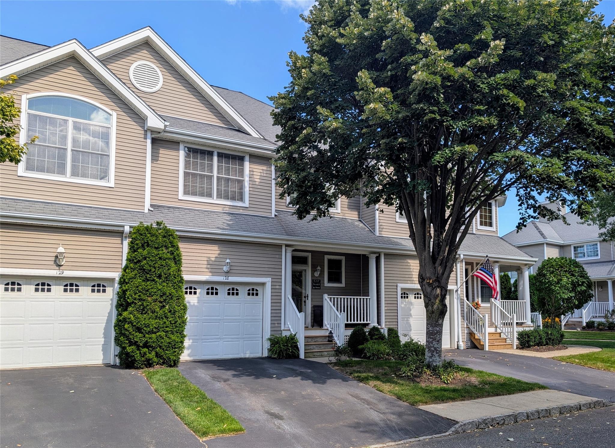 Traditional home featuring covered porch, driveway, a garage, and a shingled roof