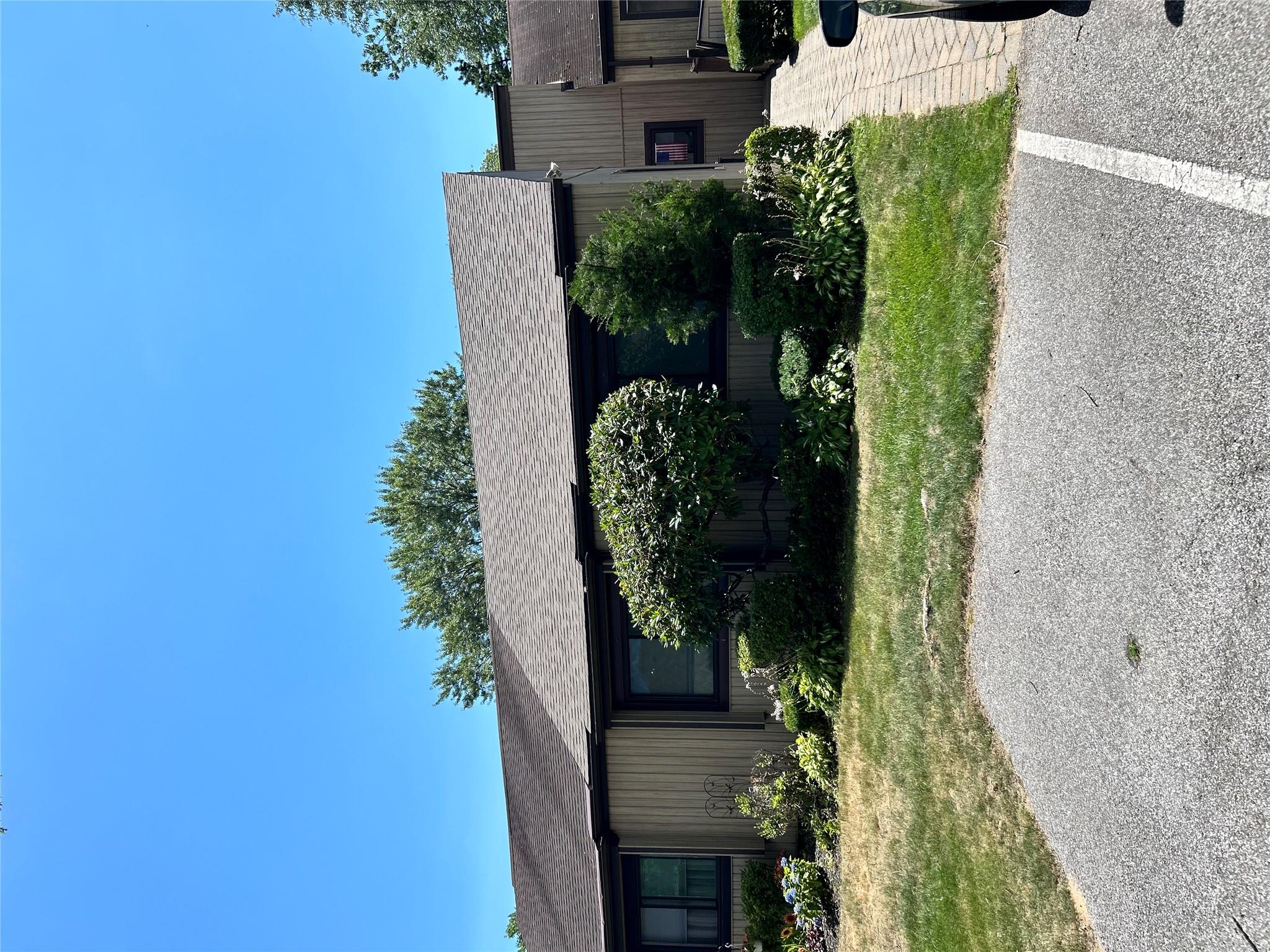 View of front facade with roof with shingles and a front yard