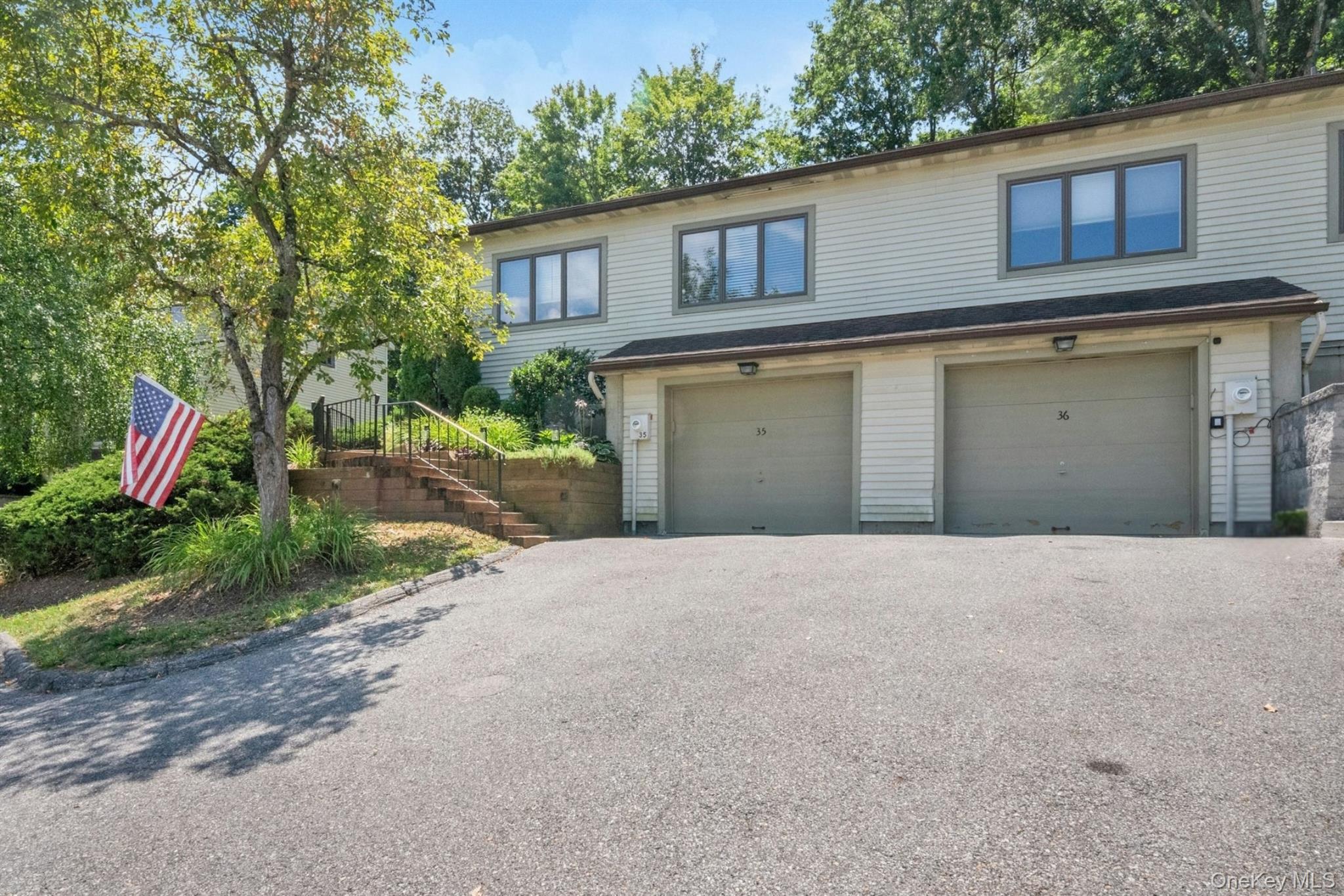 View of front facade featuring asphalt driveway, an attached garage, and stairway
