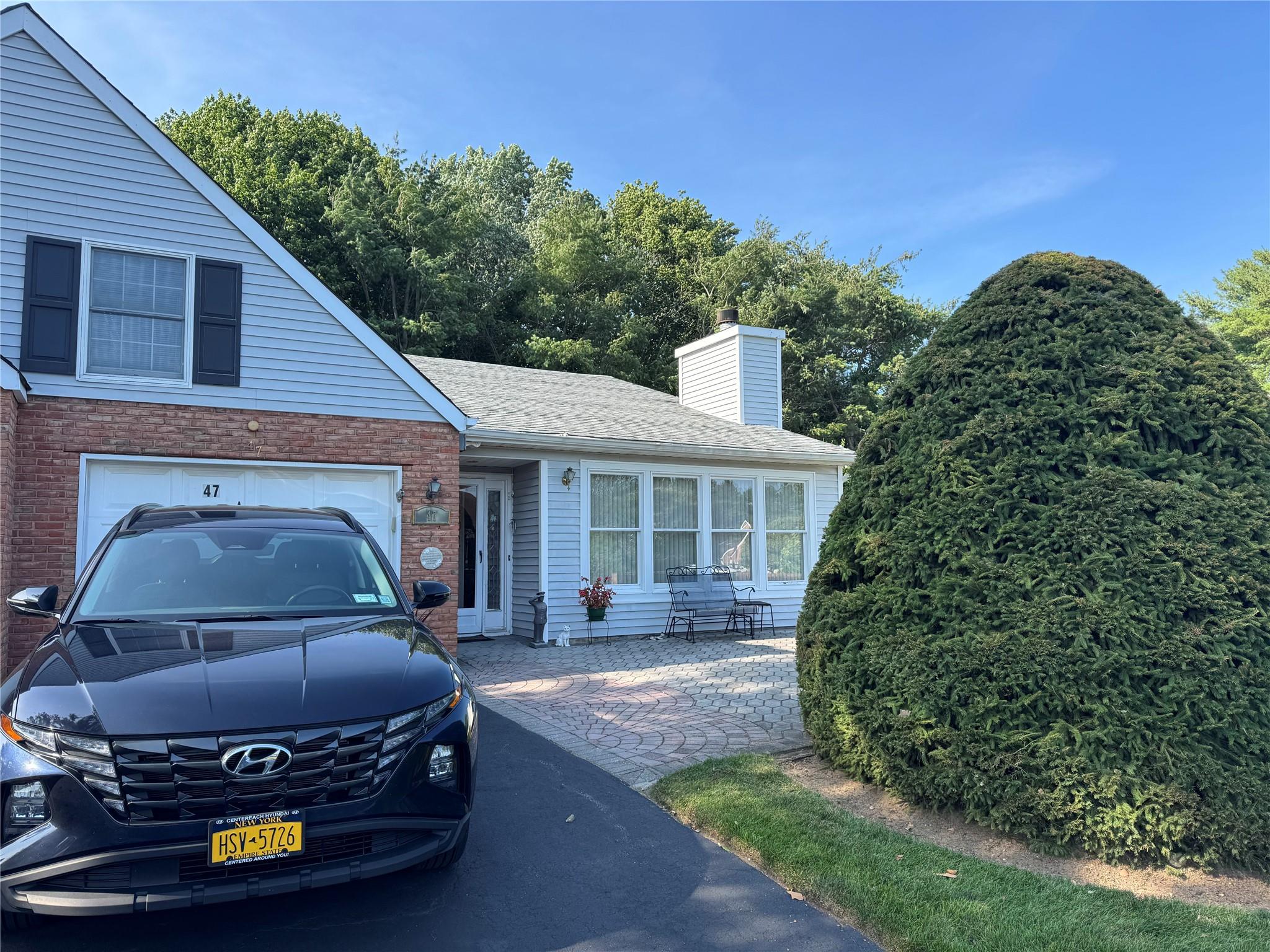View of front of house with brick siding, a garage, a chimney, and a shingled roof