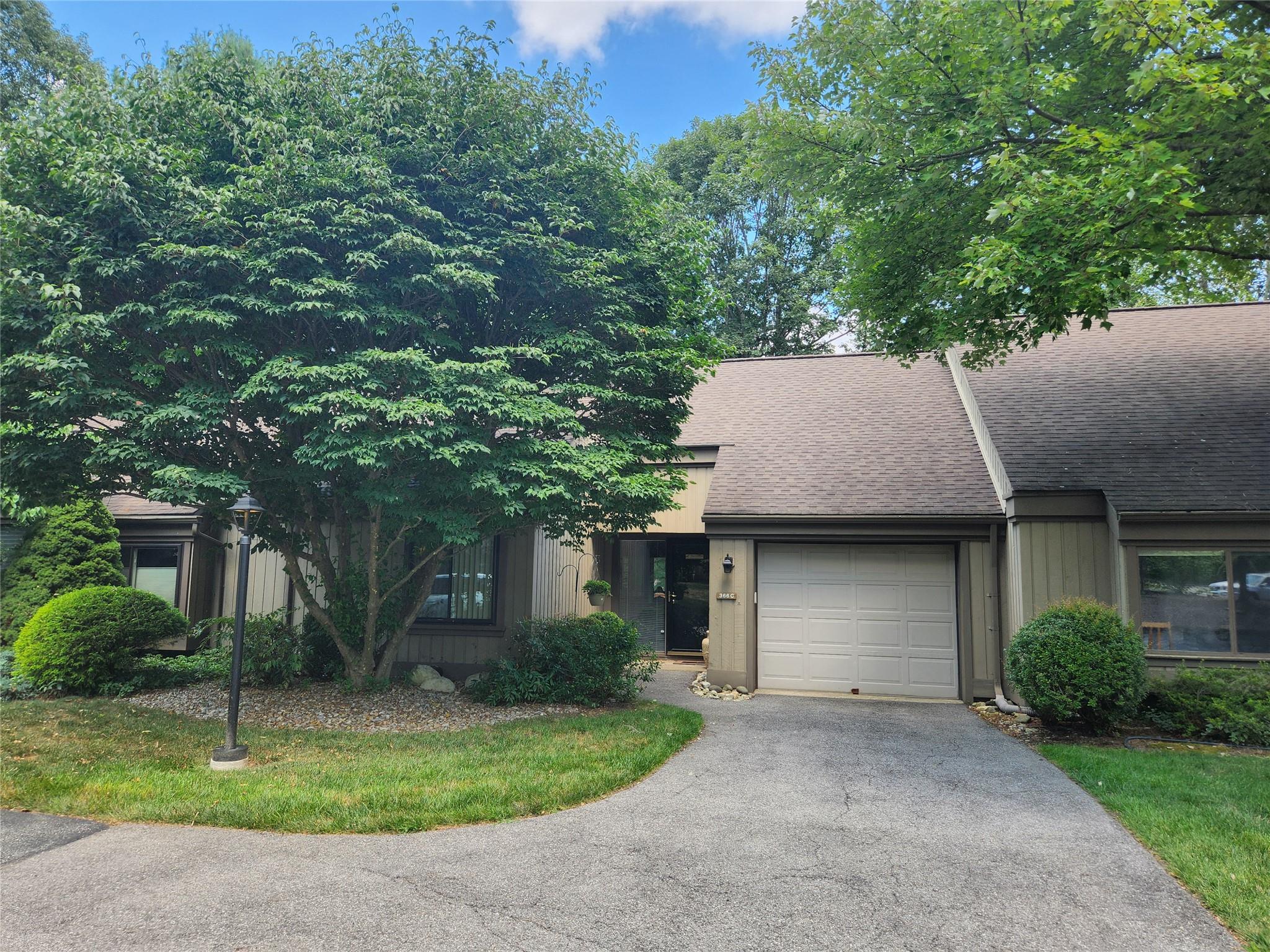 View of front of property featuring a shingled roof, a garage, driveway, and board and batten siding