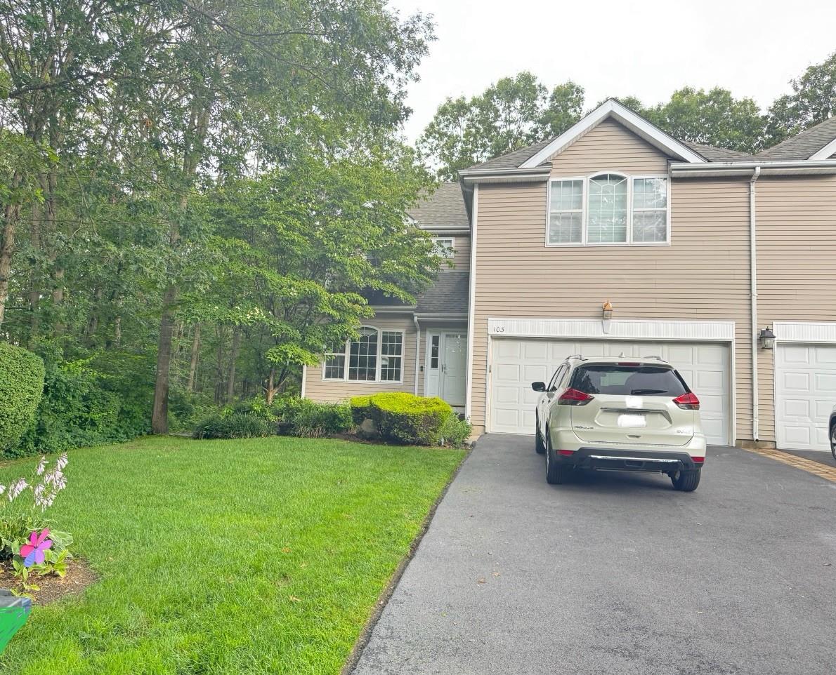 Traditional-style house featuring asphalt driveway, a front yard, an attached garage, and roof with shingles