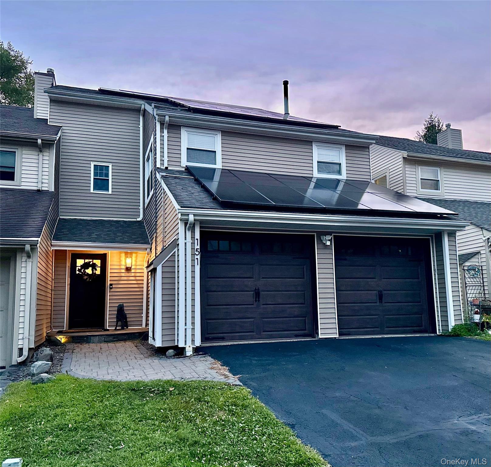 View of front of home with asphalt driveway, solar panels, and an attached two-car garage