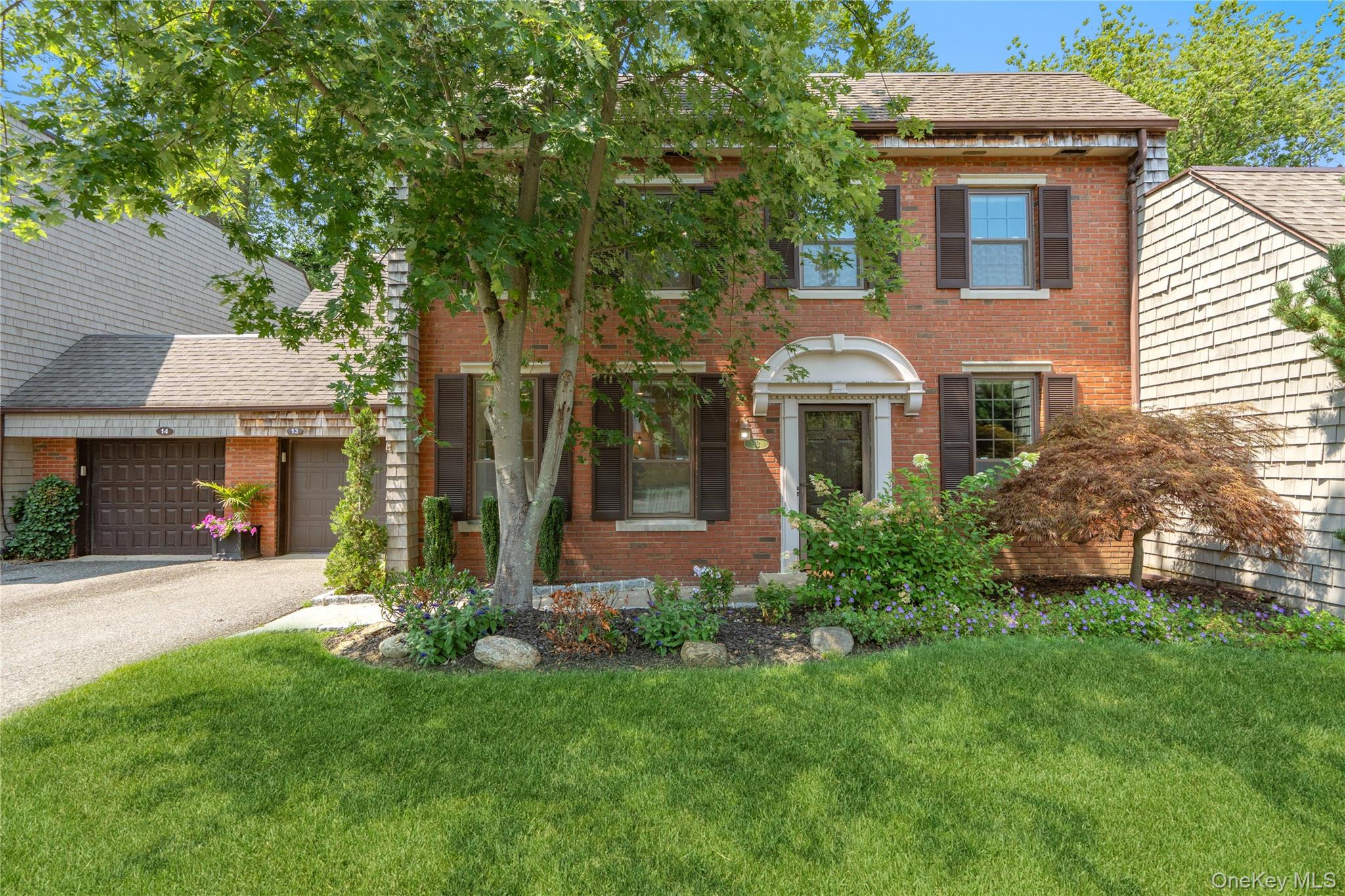 View of front of house with brick siding, driveway, and a front lawn