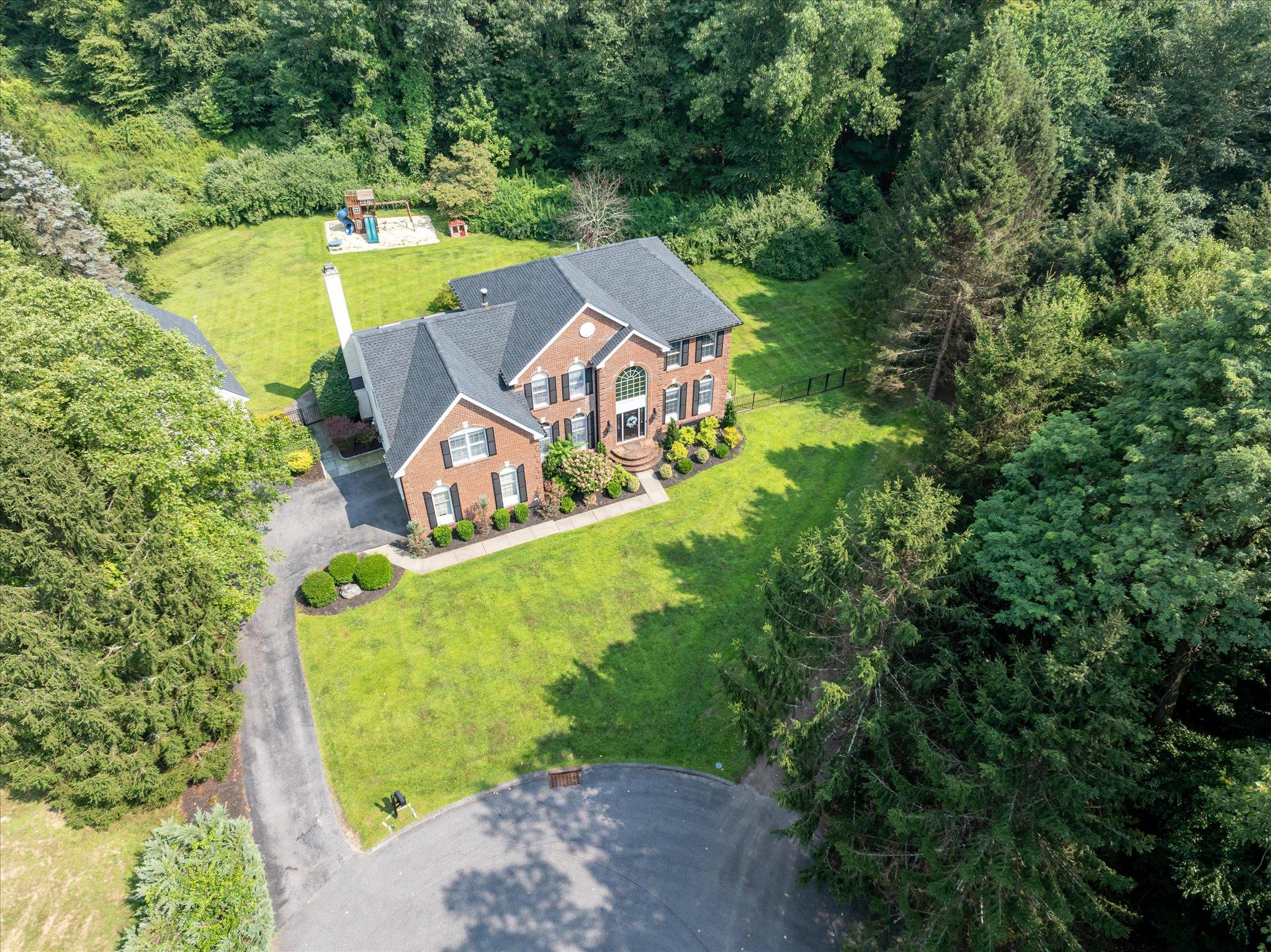 Aerial view of property and surrounding area with a heavily wooded area