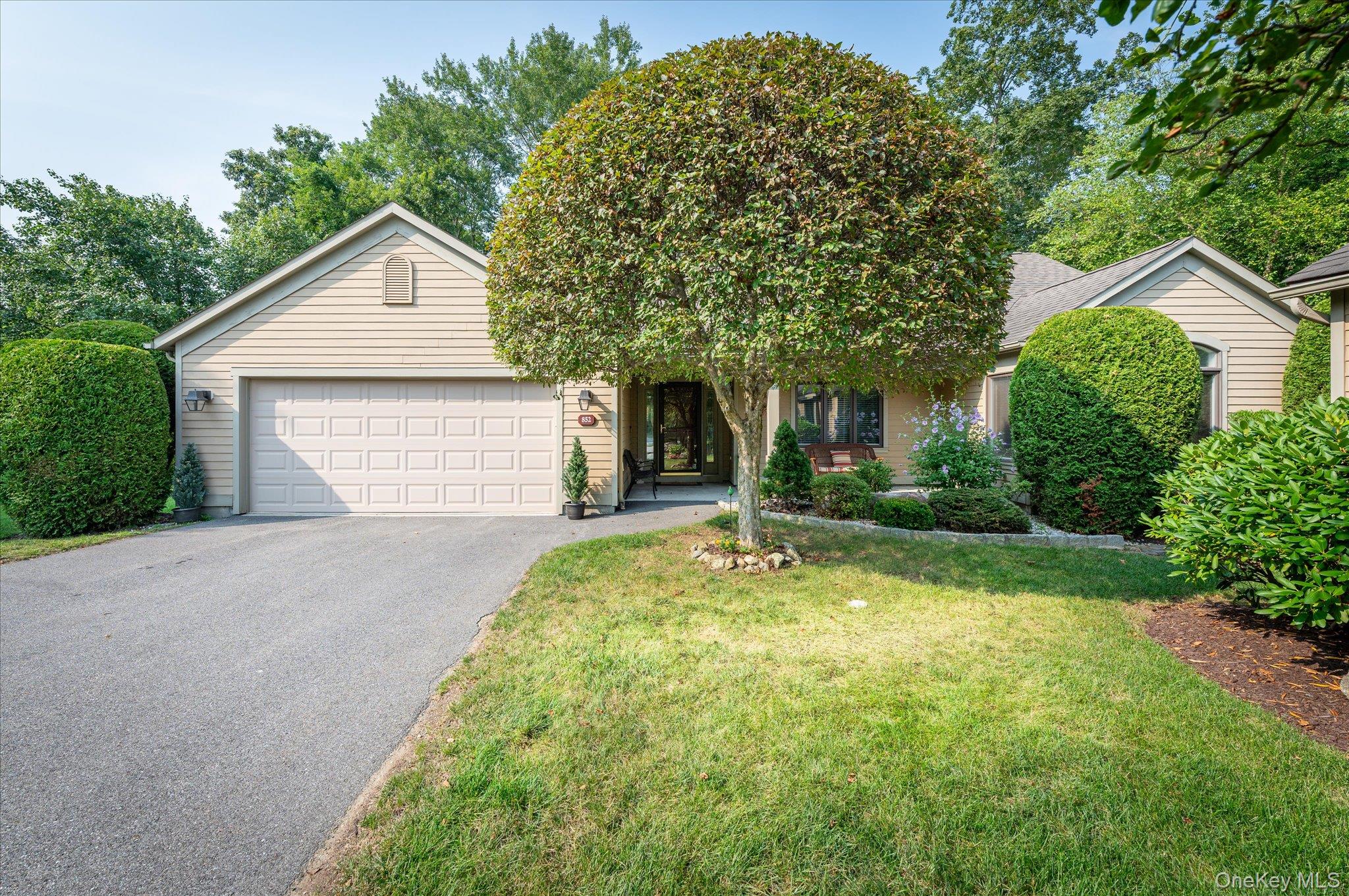 View of front of property featuring driveway, a front yard, a garage, and a shingled roof