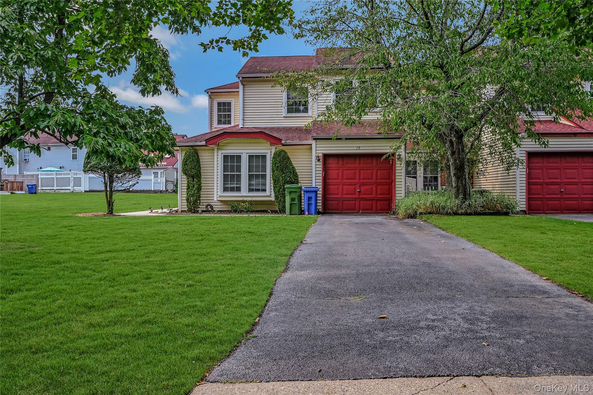 View of front of house featuring driveway, roof with shingles, a front lawn, and a garage