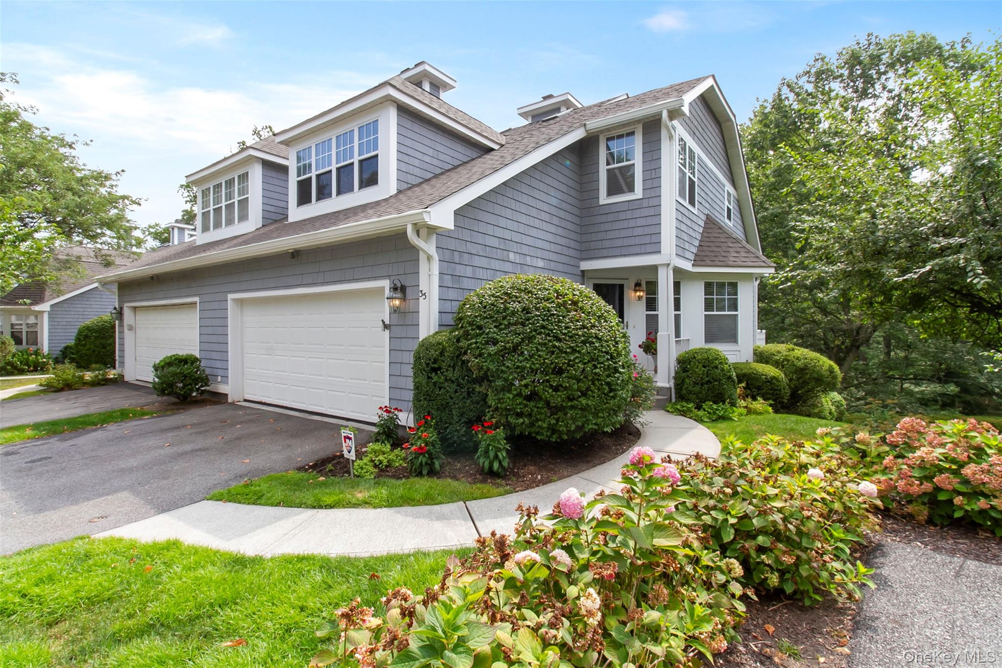 View of front of property with a shingled roof, driveway, and a garage