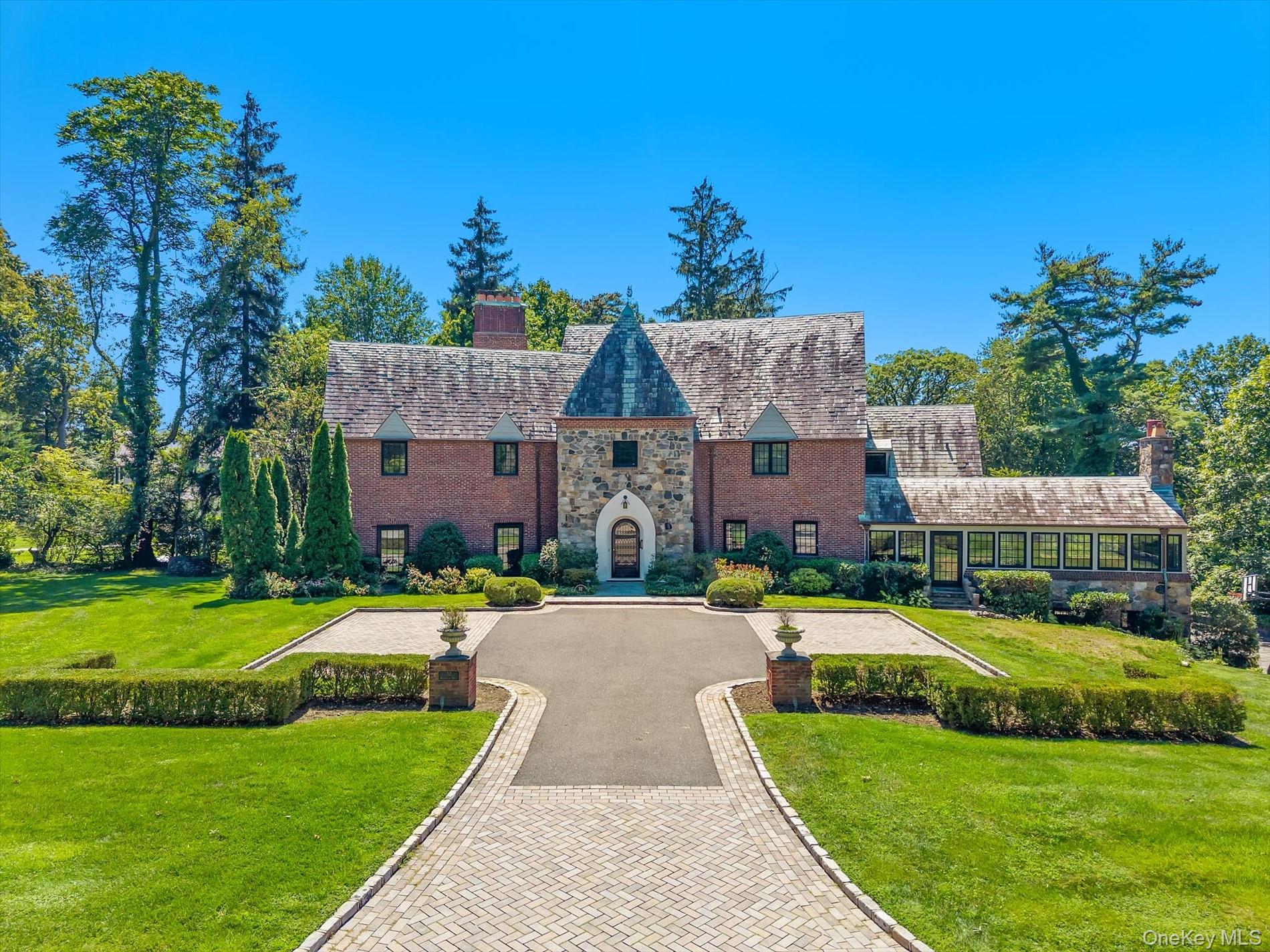 Tudor-style house featuring a chimney, a high end roof, stone siding, and a front lawn