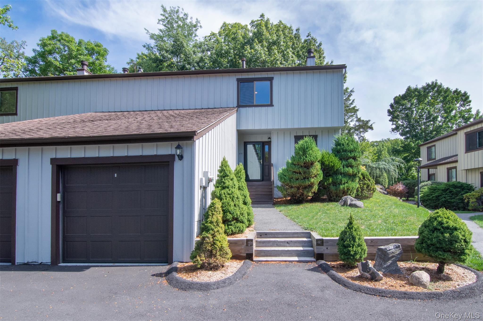 Beautiful Townhome featuring a front yard, an attached garage and board and batten siding.