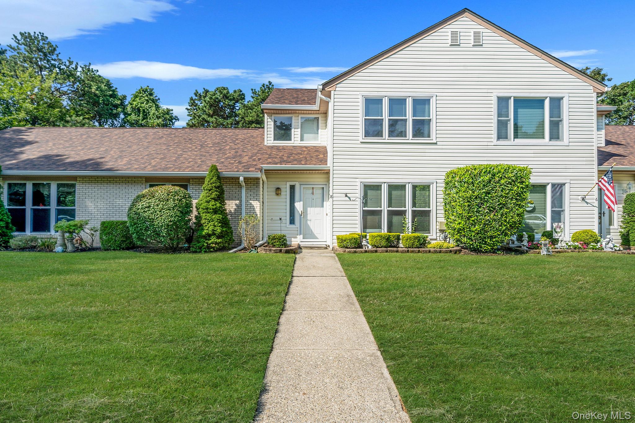 Traditional-style house featuring a front lawn, roof with shingles, and brick siding