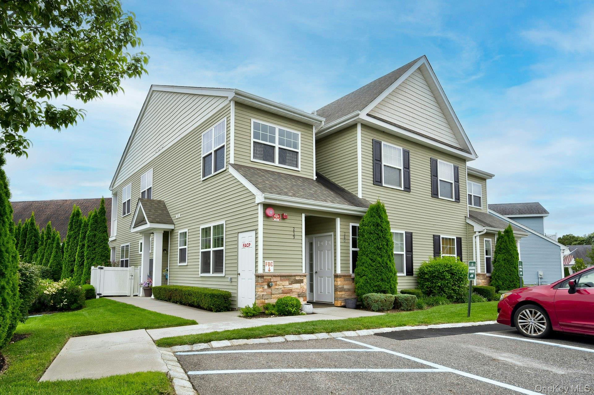 View of front of home with a shingled roof, stone siding, and uncovered parking