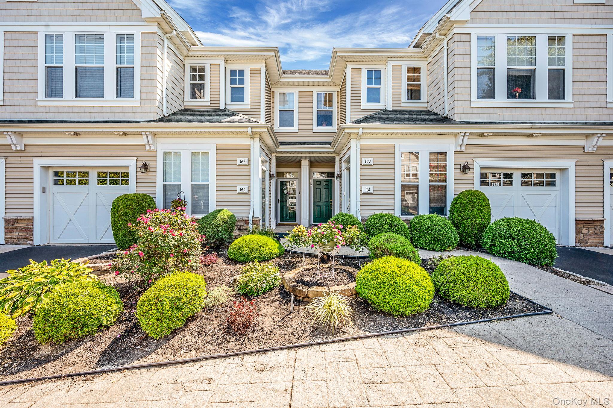 View of front facade featuring an attached garage, driveway, and stone siding