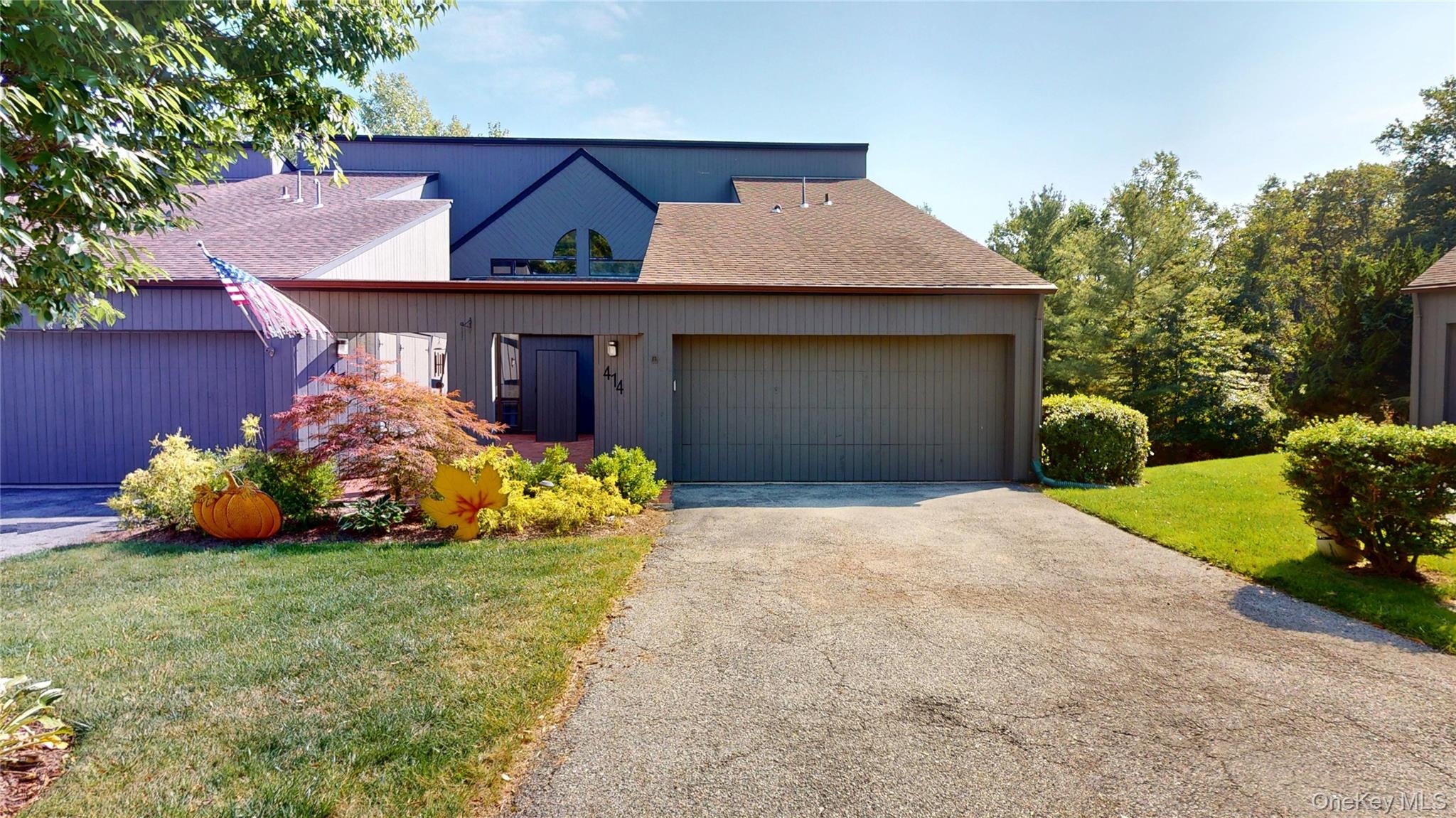 Mid-century modern home with a front lawn, a shingled roof, driveway, and an attached garage