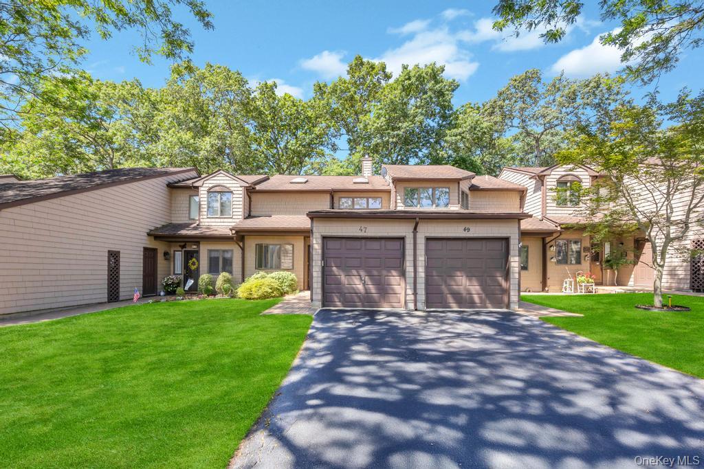 Traditional-style home with driveway, a front lawn, a garage, and a chimney