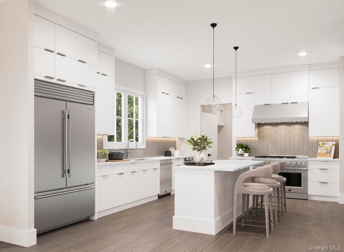 Kitchen with modern cabinets, white cabinetry, a breakfast bar area, high end appliances, and recessed lighting
