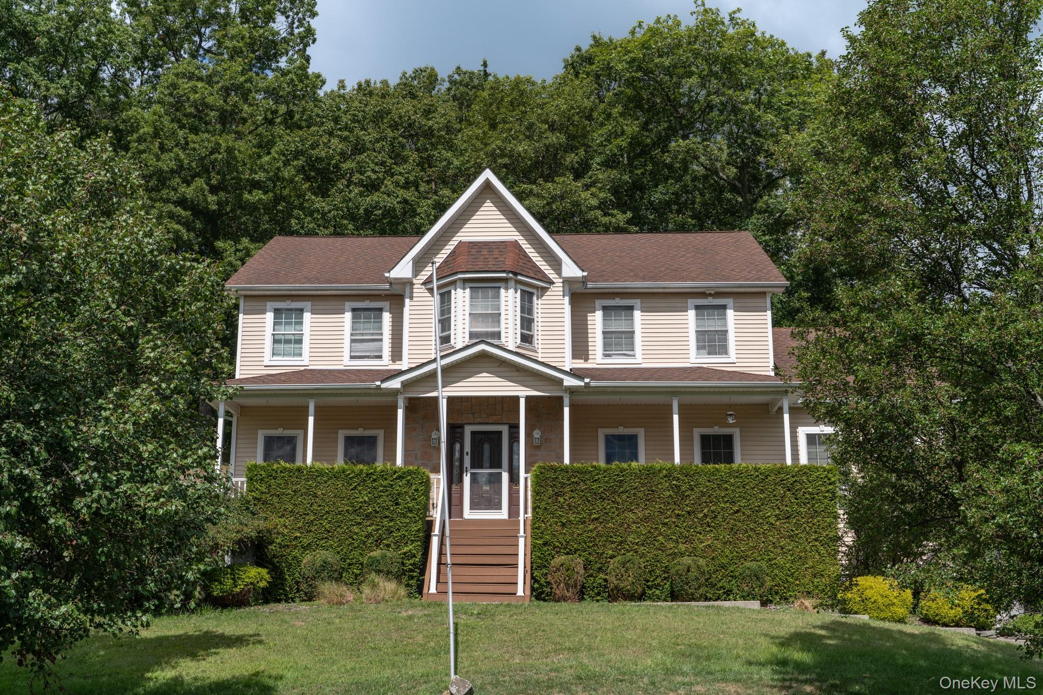 View of front facade with covered porch, a front lawn, and a shingled roof