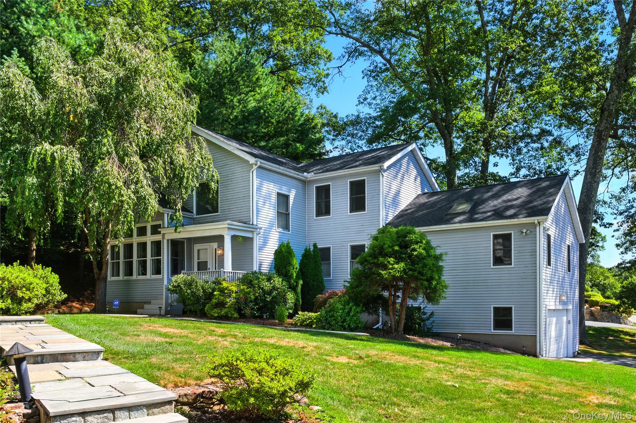 View of home's exterior with a lawn, a garage, and a sunroom