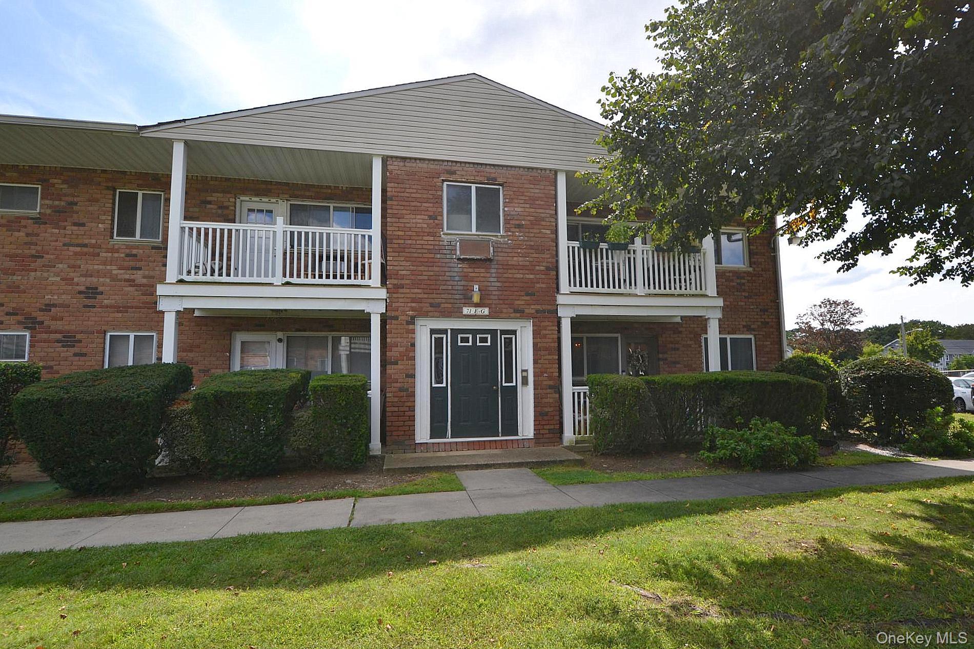 View of front of property with a balcony, brick siding, and a front yard