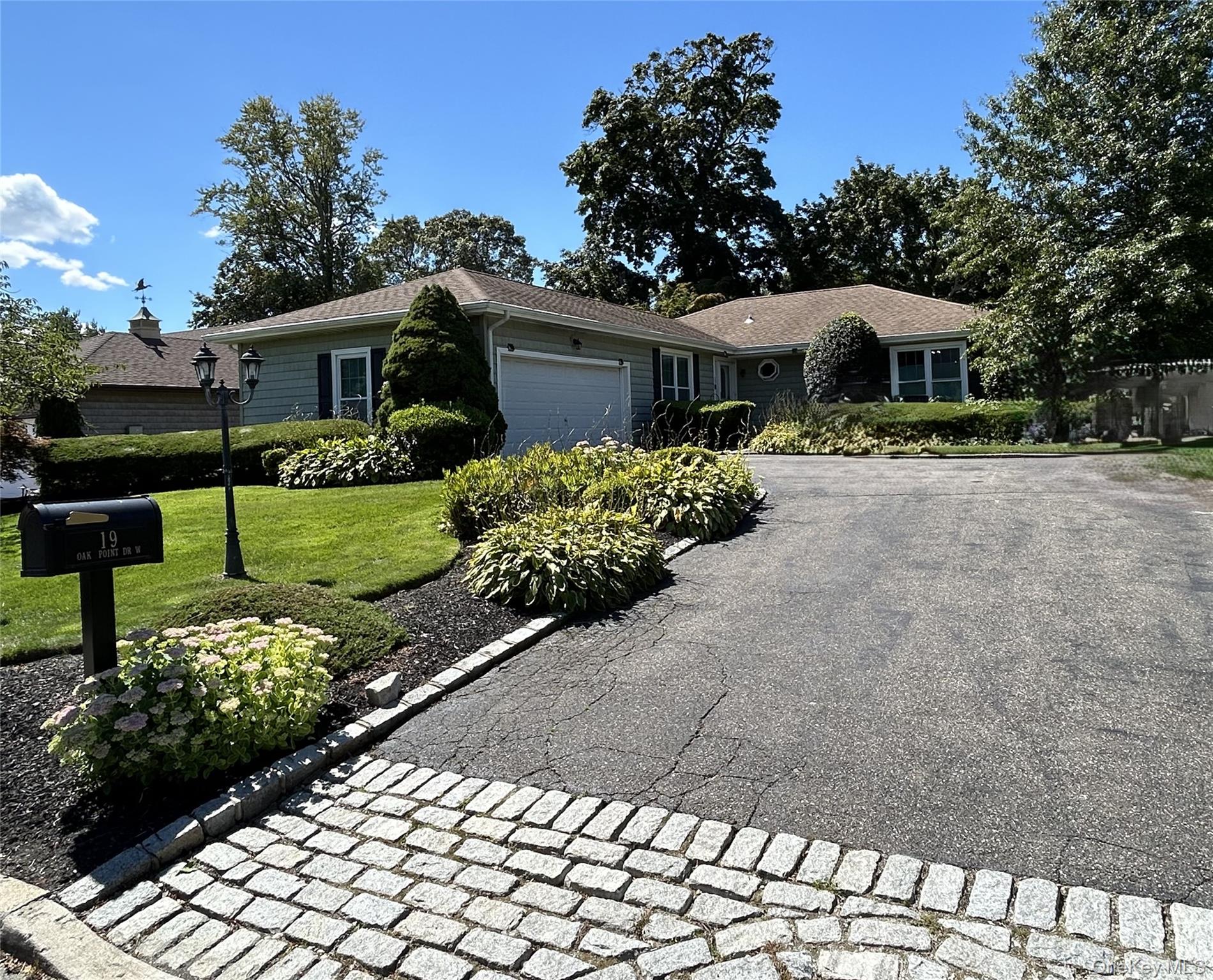 Ranch-style house with an attached garage, a front lawn, and asphalt driveway