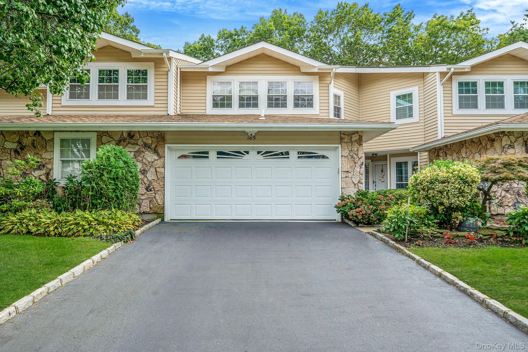 Traditional-style house with stone siding, asphalt driveway, and an attached garage