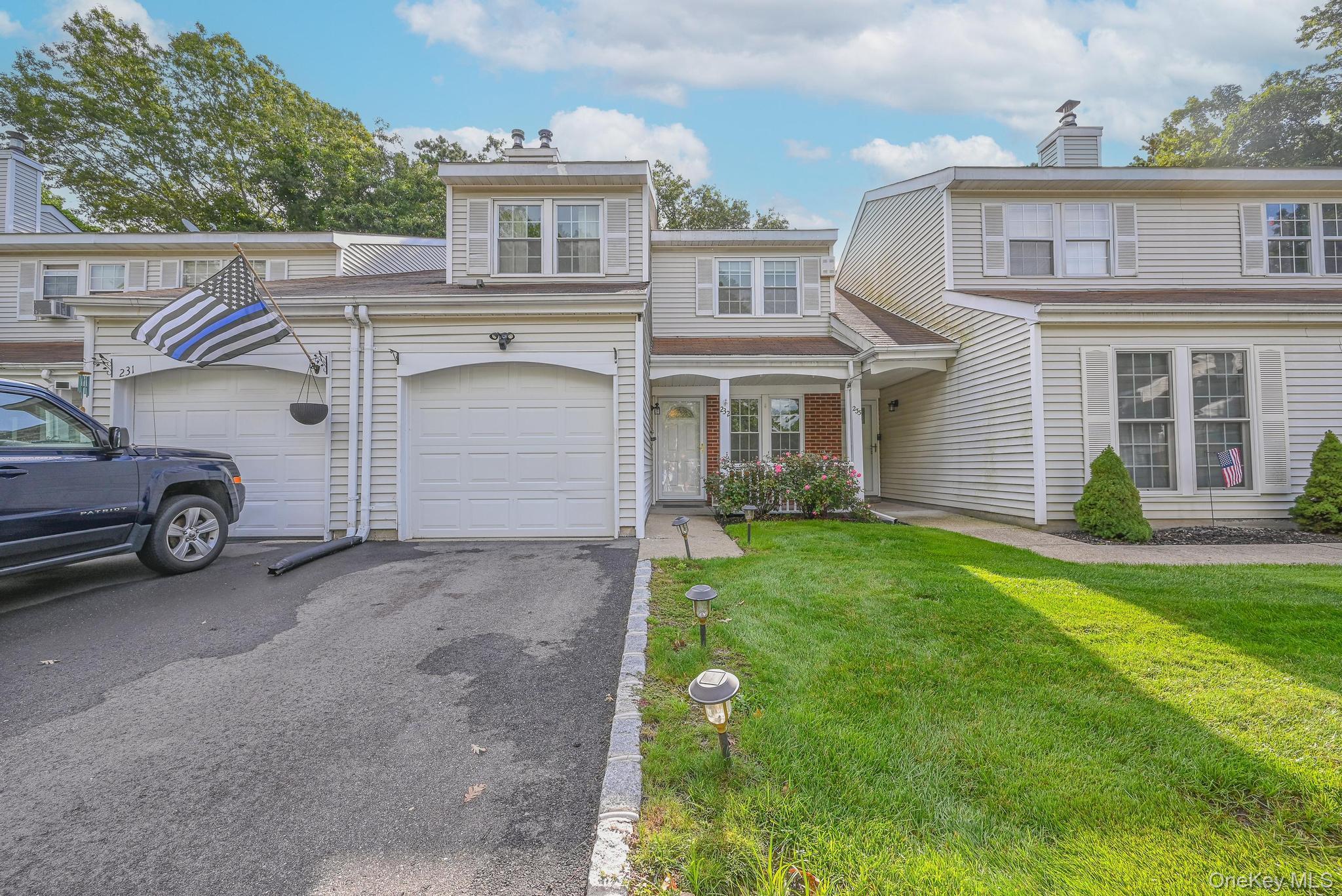 Traditional home featuring asphalt driveway, covered porch, a front lawn, and a chimney
