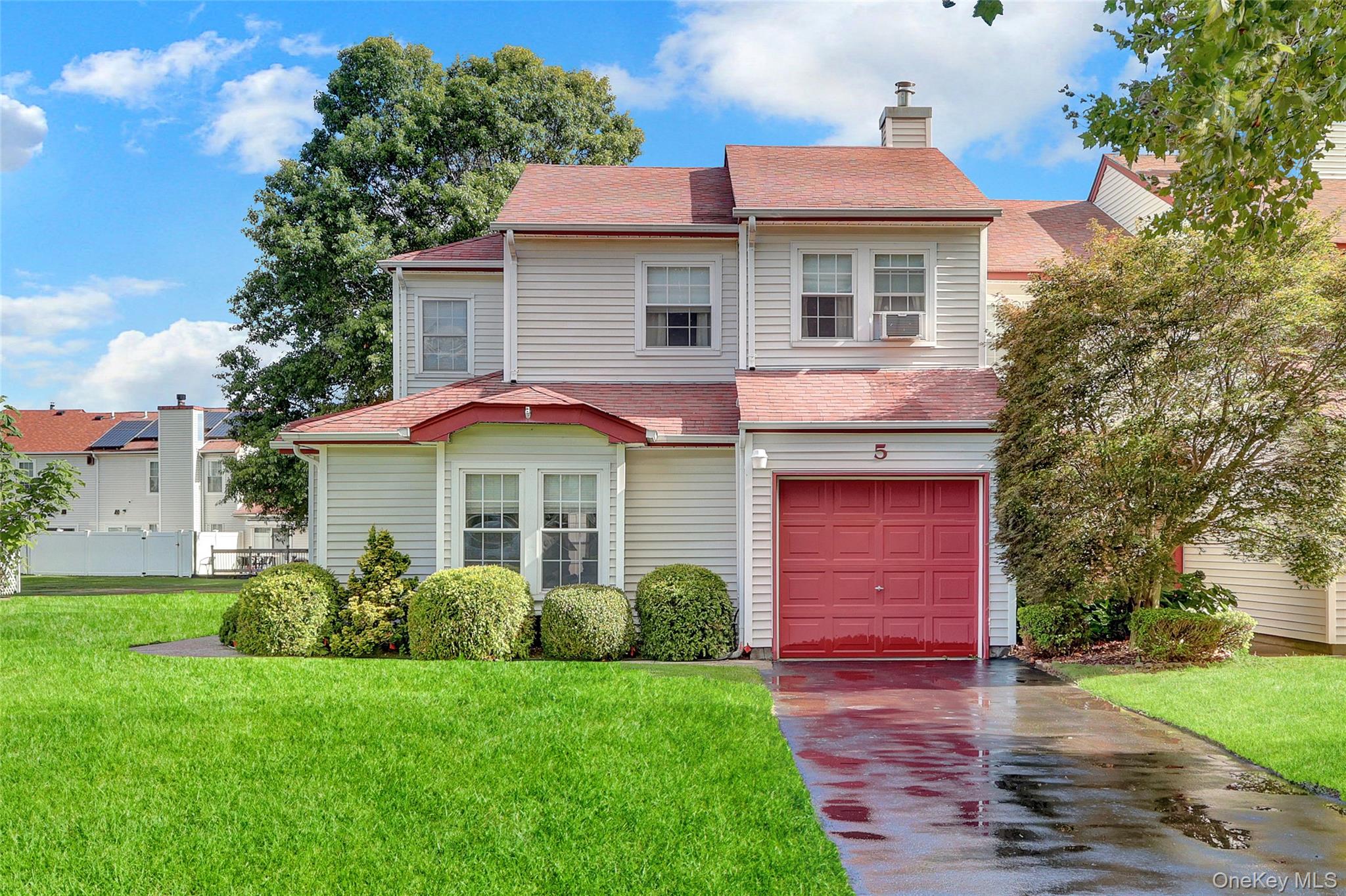 View of front of property with roof with shingles, a front lawn, and concrete driveway