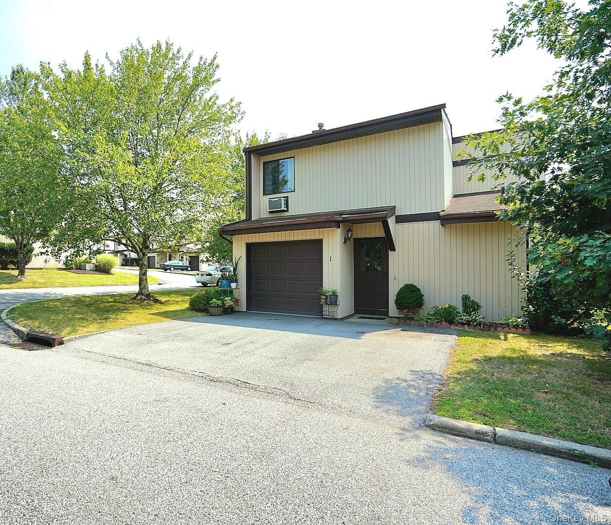 Mid-century inspired home featuring driveway, a front yard, and an attached garage