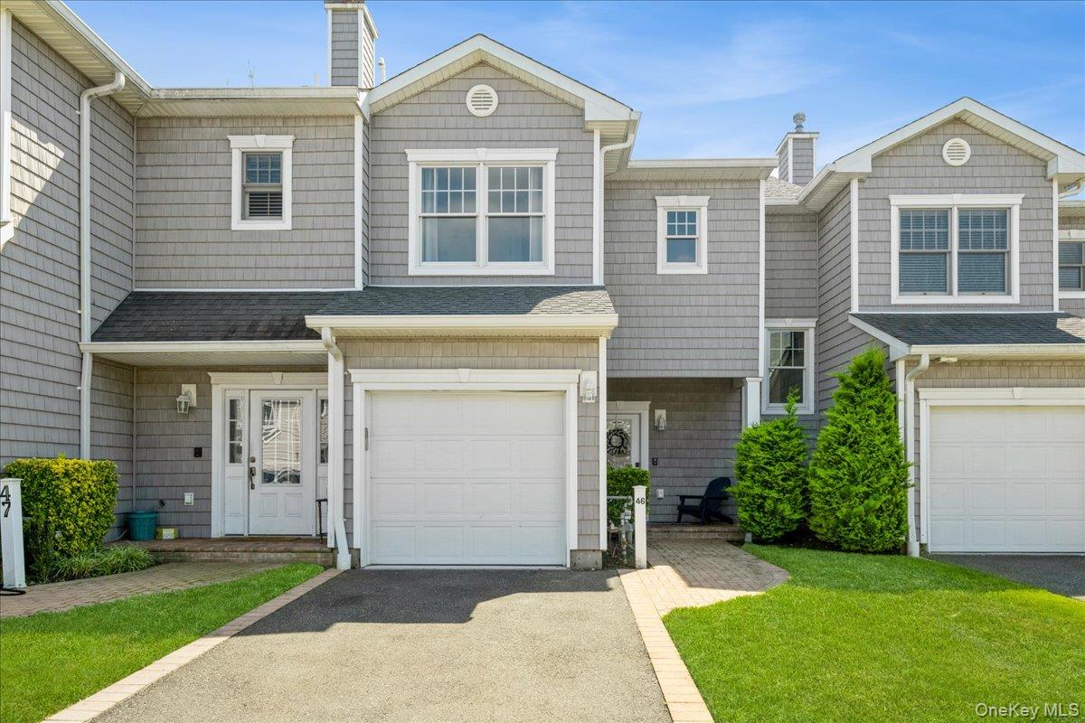 View of front of home featuring a chimney, asphalt driveway, a front yard, and a garage