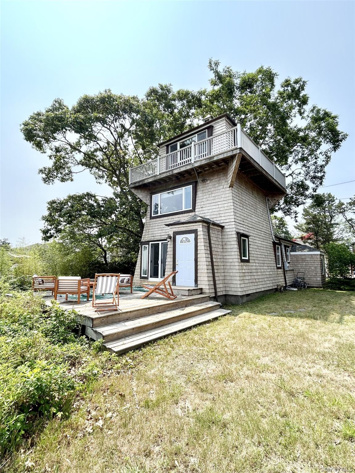 Back of property with a yard, a wooden deck, and a balcony