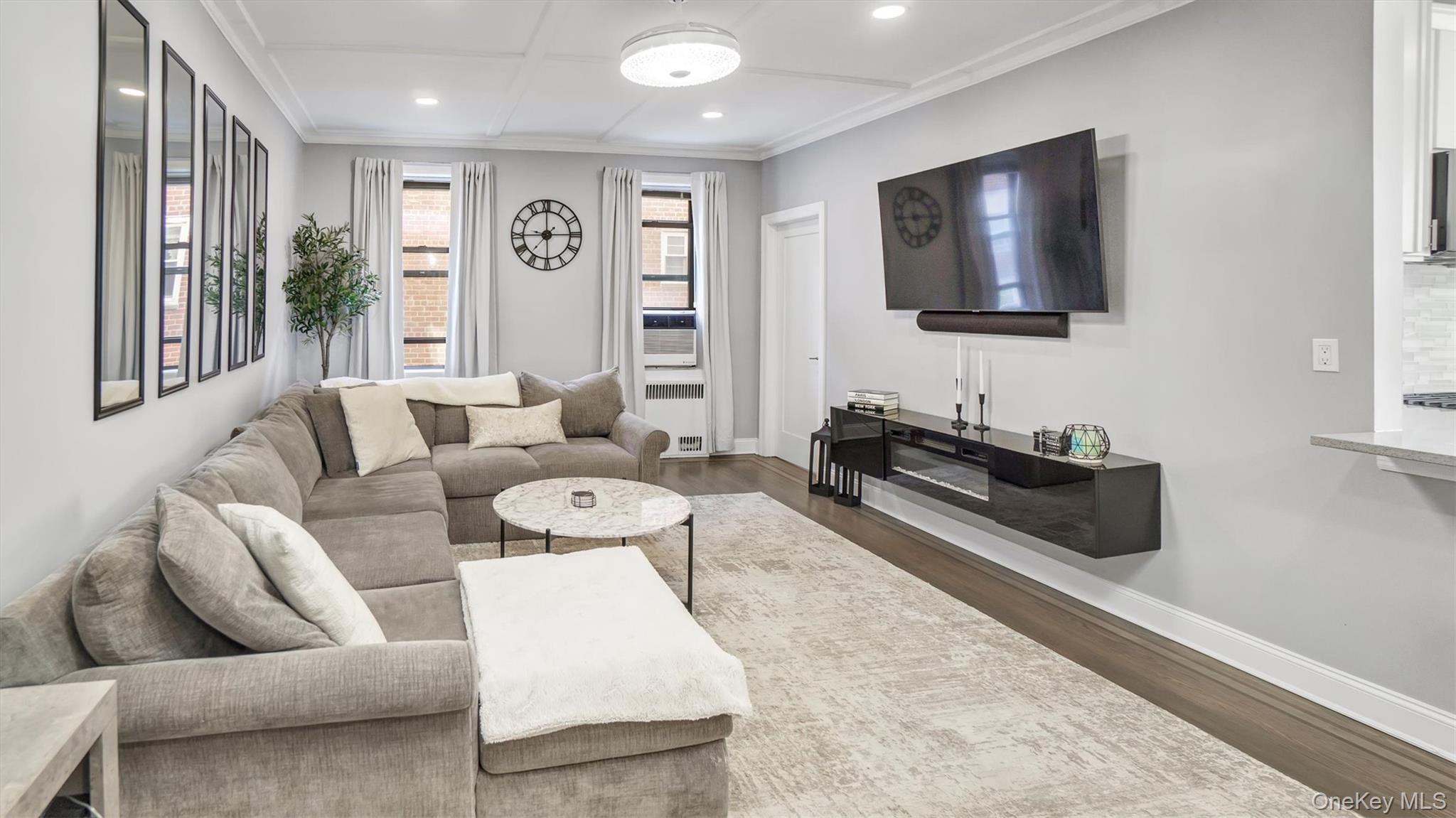 Living room with dark wood-type flooring, crown molding, and recessed lighting