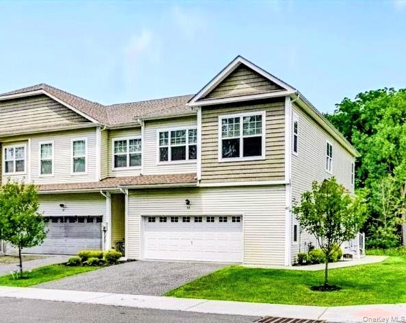 View of front of home featuring driveway, an attached garage, and a front yard