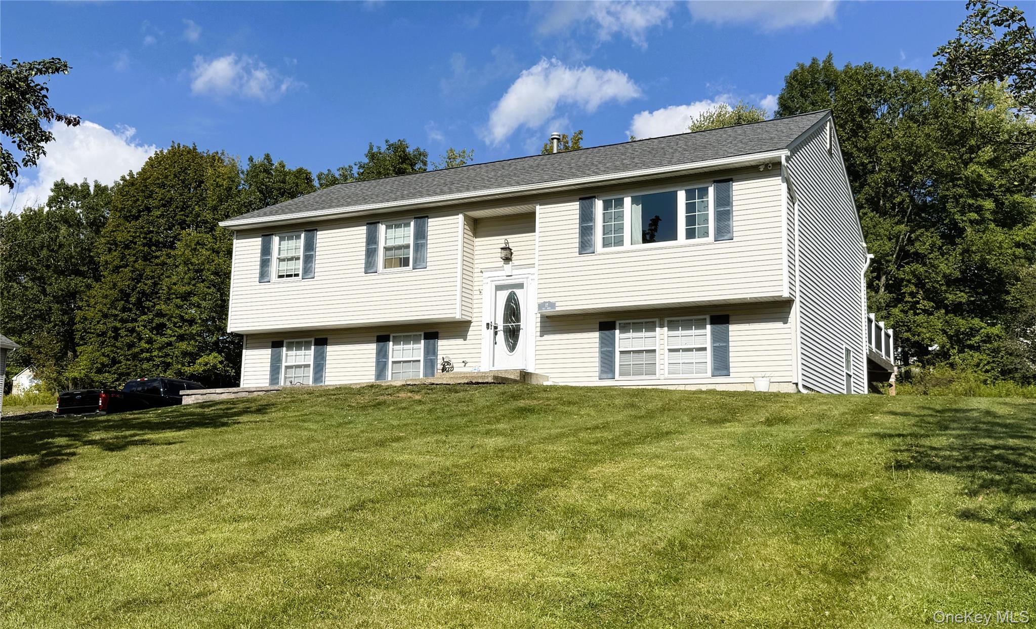 Split foyer home with a front lawn and roof with shingles