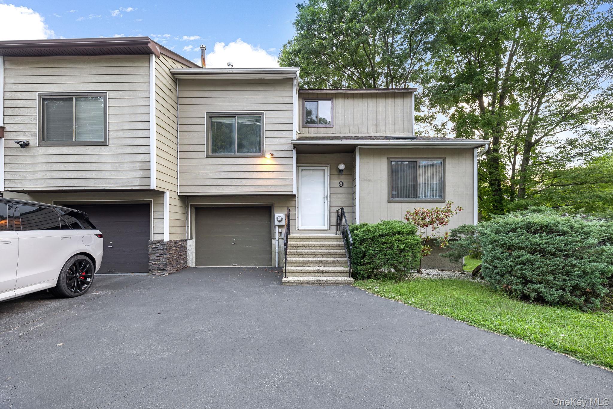 View of front of property with driveway, a garage, and stone siding