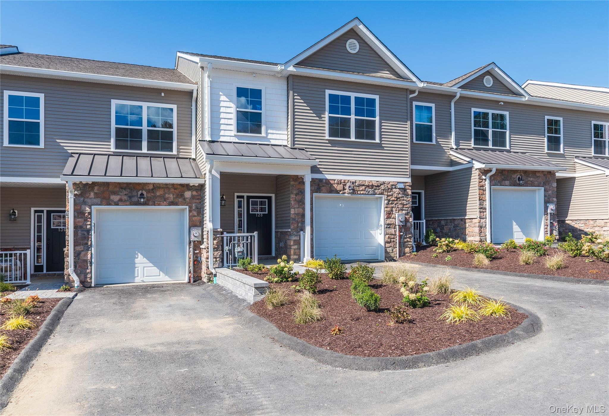 Craftsman-style home with stone siding, a standing seam roof, a metal roof, and driveway