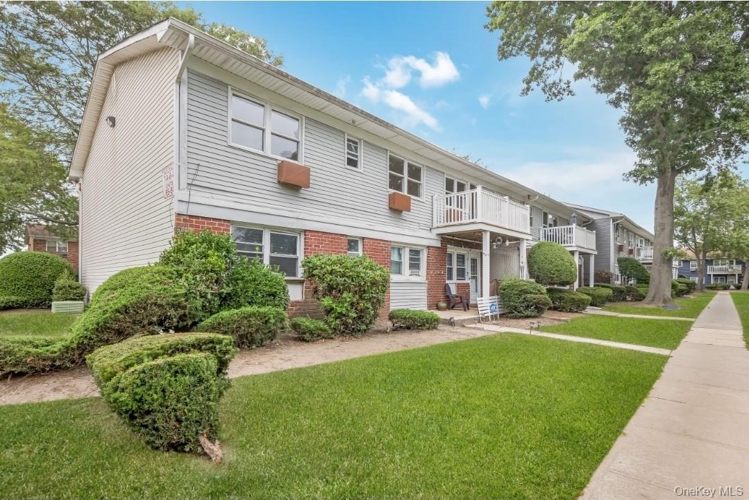 View of front of home featuring a balcony, brick siding, and a front lawn