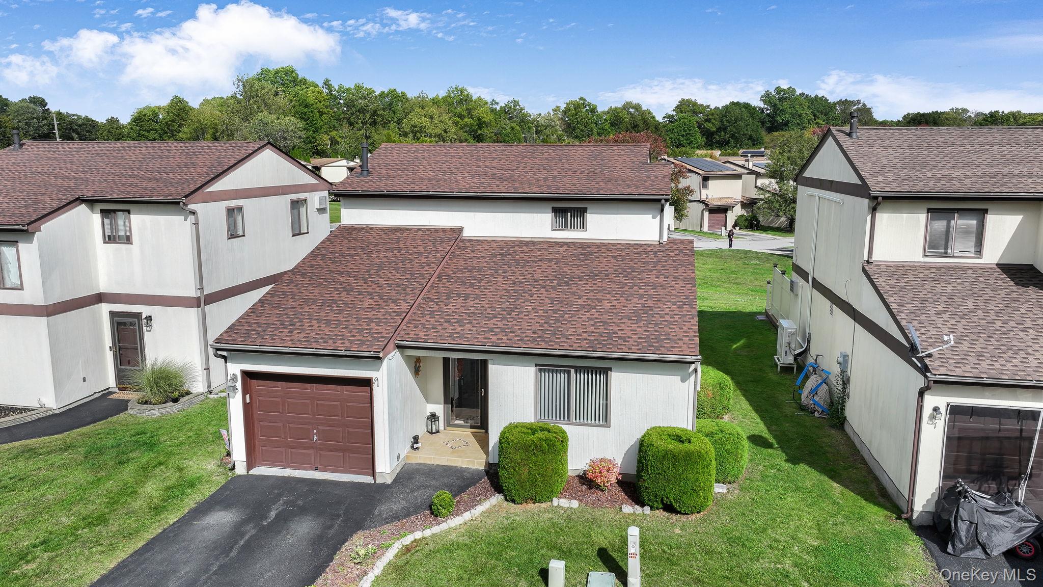 View of front of home with a shingled roof, a residential view, asphalt driveway, an attached garage, and a front lawn