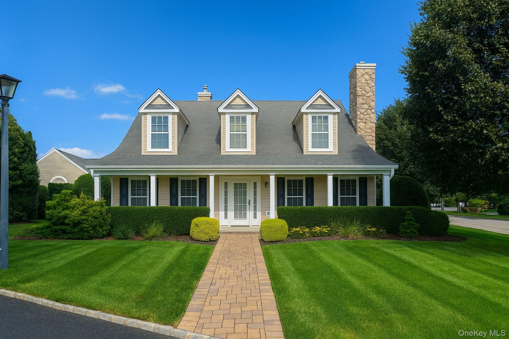 Cape cod house featuring a front lawn, a chimney, and a porch