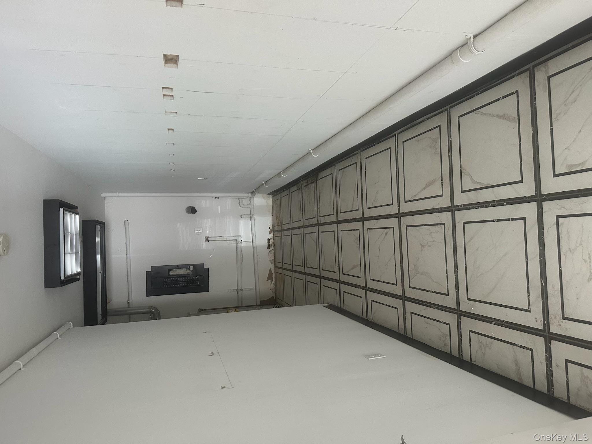 Corridor featuring baseboards and electric panel